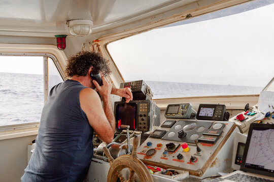 Fisherman monitoring navigation equipment while using radio