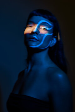 Creative face paint with blue lighting in studio