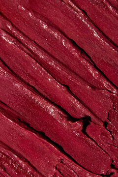 Bright red lipstick texture smeared with waves and imperfections