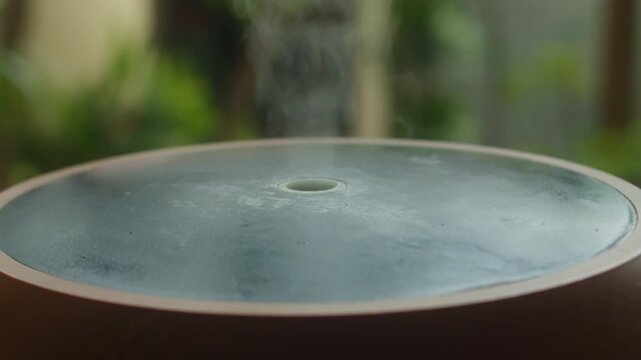 Ultrasonic humidifier creating relaxing atmosphere with visible vapor in a cozy indoor space. Close up Wood Grain Aroma Diffuser Releasing Steam by a Window.