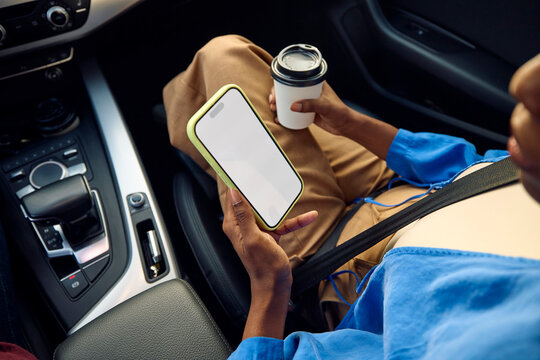 Woman looks at a blank screen of a mobile phone while in a car