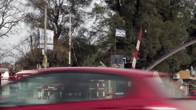 Car Driving Past Raised Railroad Crossing Gate with Argentine Flag in General Rodriguez, Buenos Aires Province