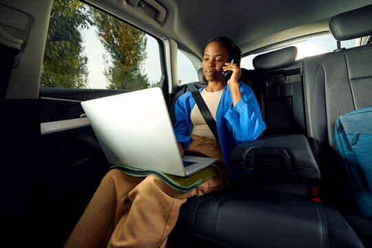 Woman commutes in the back of a car, working remotely