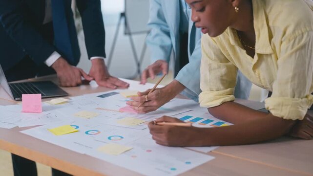Business team takes notes, reviews documents, and analyzes financial data meeting in office.