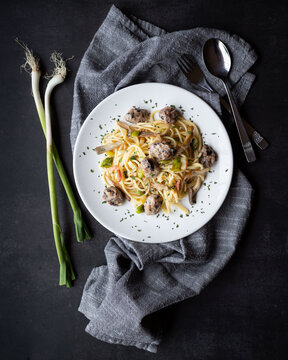 Plato de pasta espagueti con trozos de salchicha, setas, bacon y ajos frescos