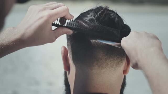 Close up hands cutting hair scissors comb. Male undercut haircut back view.
