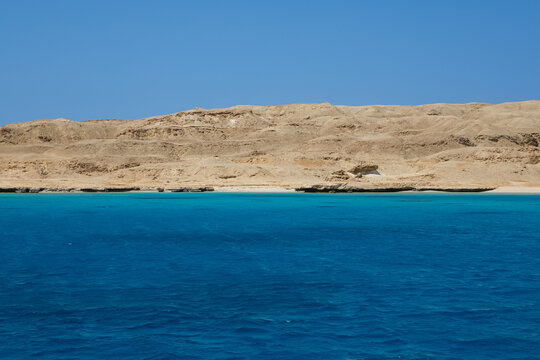 Scenic coral reef in turquoise ocean water near desert coastline