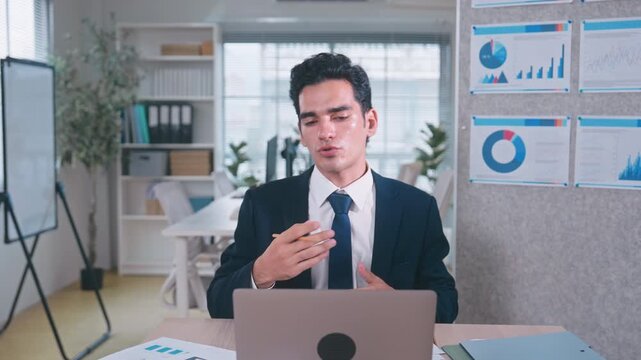 Businessman on suit speaking and explaining ideas to camera during a video call meeting in office
