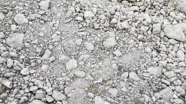 Dry clay soil with white limestone chunks and gravel surface
