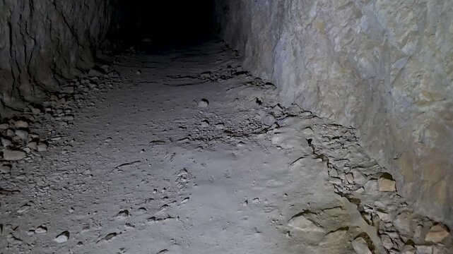 Smooth camera movement inside a dark cave tunnel revealing a hidden hoard of ancient patinated coins inside a broken pipe.