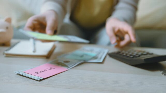 Hands are sorting banknotes into labeled stacks for cash allocation, with a calculator, notebook and cropped piggy bank nearby as sorting links each label to visible financial priorities.
