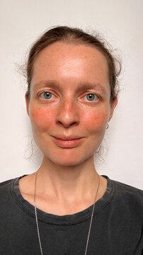 Selfie of smiling woman 30-35 year old looking at camera over white background close up.