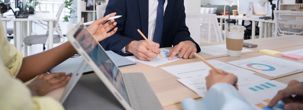 Business team discussing financial charts and data on a digital tablet during a meeting in a modern office corporate strategy, and teamwork.