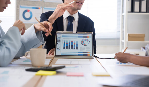 Business team discussing financial charts and data on a digital tablet during a meeting in a modern office corporate strategy, and teamwork.