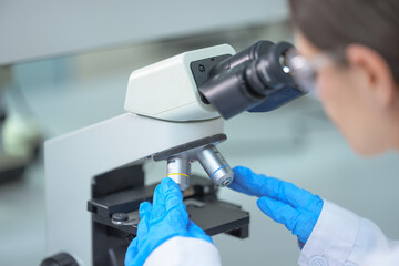 Gloved hand rotating a microscope objective turret in a sterile workspace with shallow depth of field as public health labs race to test for Ebola, mpox and avian influenza © ultramansk