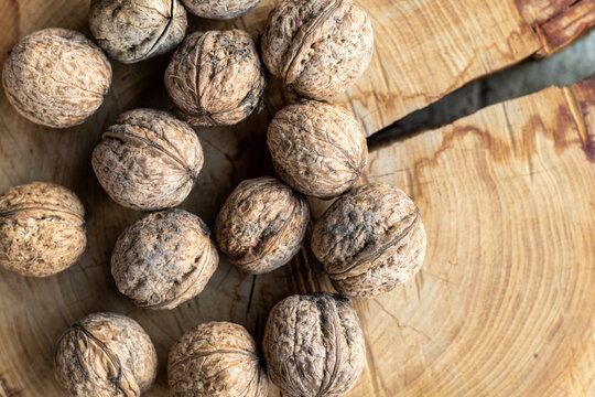 Whole walnuts arranged on a rustic wooden slice background   