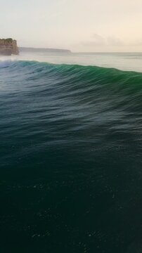 Drone view of breaking ocean waves with sunset tones in Bali