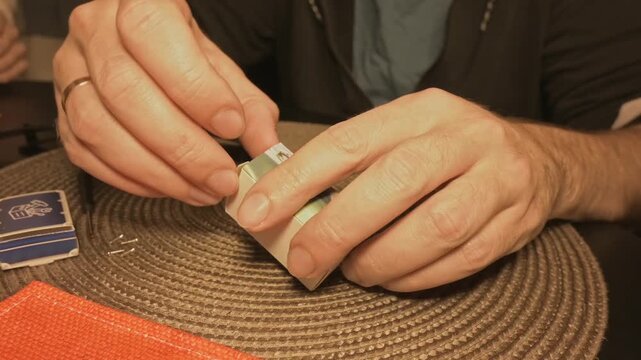 Close-up of hands opening a small box from an Advent calendar and taking out miniature car seats for a model car assembly kit. Unboxing miniature parts and preparing components for a DIY hobby project