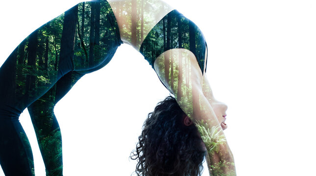 Double exposure of woman in yoga wheel pose with green forest, tall trees and ferns blended into her body