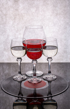 Glasses containing liquid on a vinyl record against a gray background