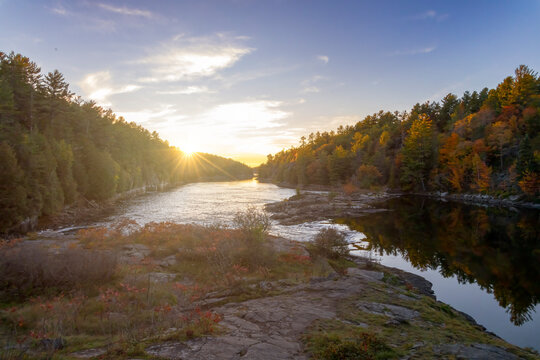 Scenic sunset view at Recolett Falls in French River Provincial Park, Ontario, with serene river reflections and lush forests.