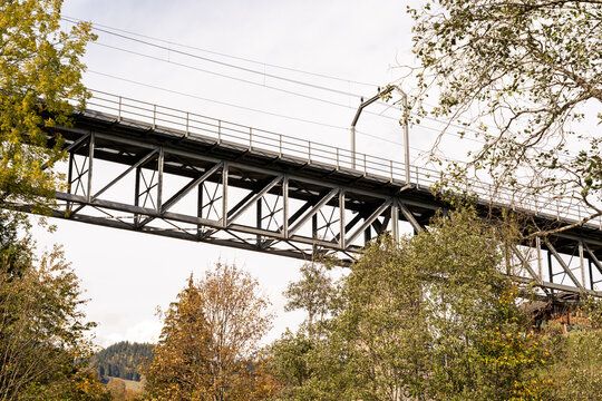 Steel truss railway bridge on the 1000 mm metre gauge railway route between Montreux and Zweisimmen in Switzerland, with overhead electric lines in an alpine autumn landscape.