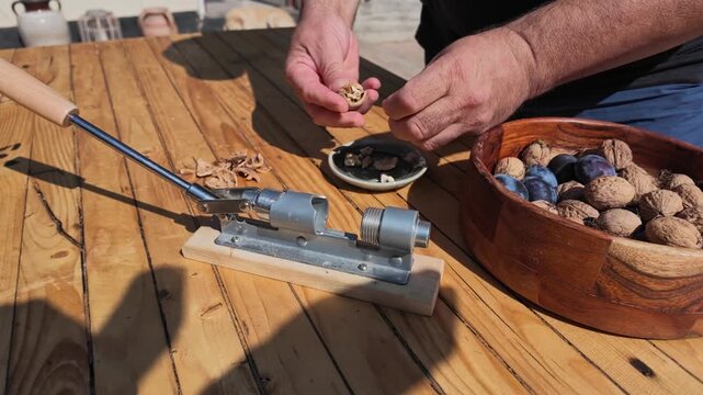 POV Clip of Hand Cracking Walnuts Slowly at the Table Outdoors