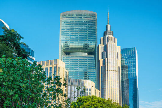 Contemporary glass office towers and green trees in modern urban center of Guangzhou city, China. Corporate architecture, financial business, commercial property, high-rise development