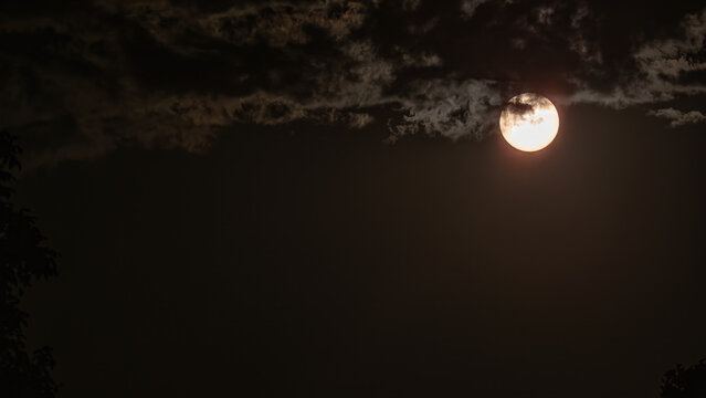 Sun peeking through clouds photographed with an ND filter.