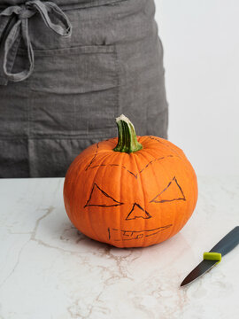 Carving a pumpkin for Halloween with a knife, festive decoration idea for autumn celebrations and events