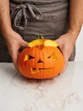 Pumpkin carving with spooky face design, Halloween preparation for festive events and gatherings