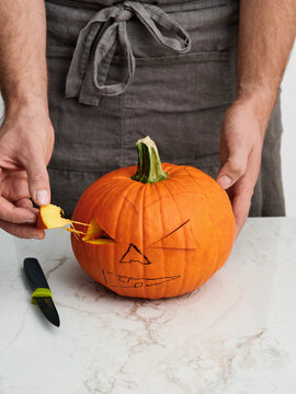 Pumpkin carving process with a knife and scooped pumpkin guts, Halloween decoration activity for festive gatherings