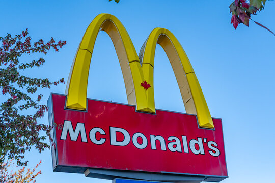 Vancouver, BC, Canada-September 27, 2026: McDonalds sign against blue sky with small Canadian Maple Leaf symbol on golden arches.