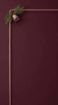 Vertical photo of minimalist Christmas frame background with copper wire, bell, and pine branch on dark burgundy paper. Copy space for text holiday greeting card template