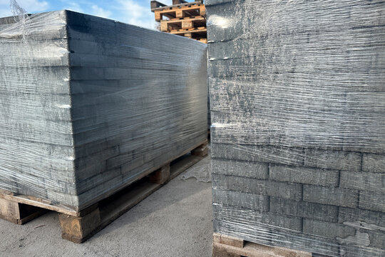 Wrapped pallets of dark concrete blocks in outdoor storage