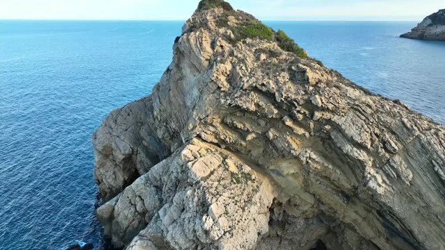 Aerial rotation around a large dramatic sea stack and layered cliff