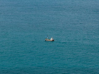 Aerial view shows a wooden whale watching tour boat navigating calm open water in Husavik, Iceland, with passengers visible onboard during an excursion. © Aerial Film Studio