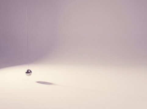 Metal ball suspended by a thread over a surface