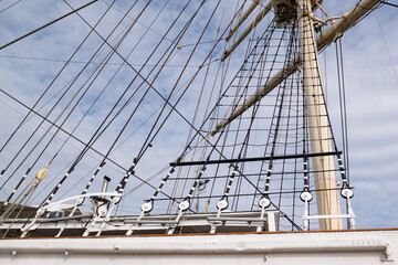 Low angle view of a historic sailing ship mast featuring complex rigging ropes, steel cables, and rope ladders © MarijaBazarova