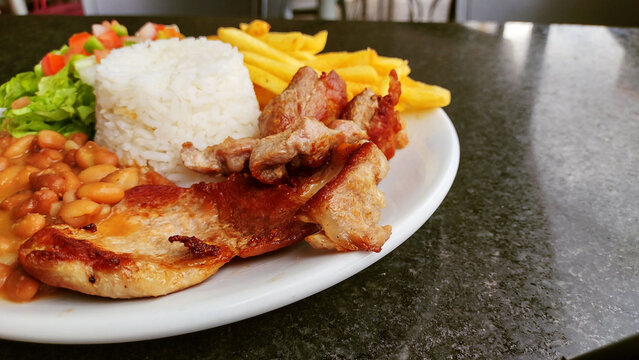 Delicious Brazilian Feijoada with Rice Beans Meat and Fries on a Plate
