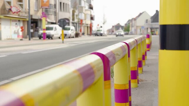 Colored pedestrian railings along an urban street slow motion yellow and pink barriers between the road and the sidewalk