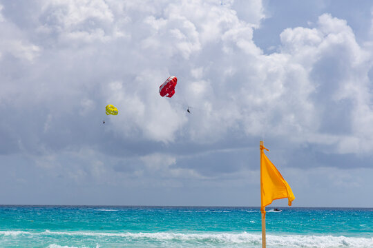 Yellow Beach Warning Flag and Parasails Over the Sea in Cancun, Mexico