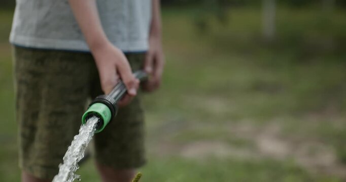 Close-up children hands watering plants in backyard. 4K 10-bit