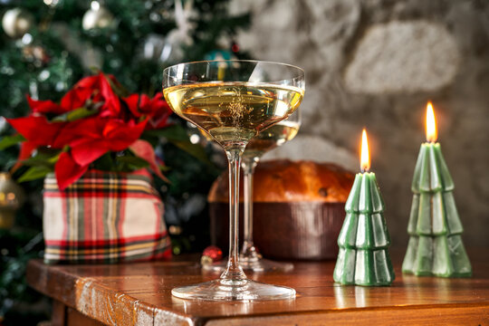 Champagne and panettone celebrate Christmas with candles and poinsettia on a warm festive table