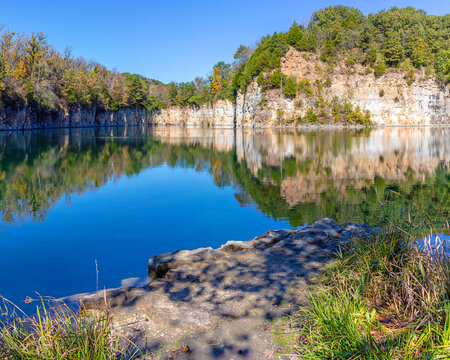 Limestone bluff reflected in a water filled abandoned quarry in rural Missouri