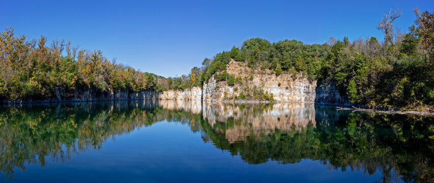 Limestone bluff reflected in a water filled abandoned quarry in rural Missouri 