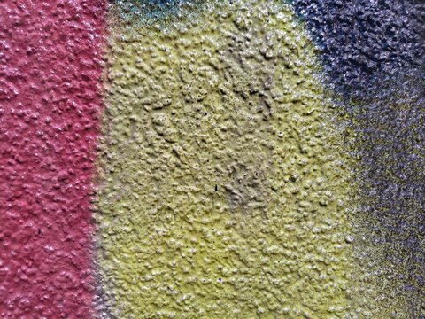 Glossy bumpy paint in three zones: matte red on the left, yellow-green in the center and dark navy-grey on the right. Light catches the raised surface in small highlights.