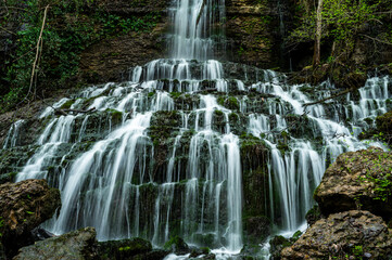 Wide cascading waterfall over mossy rock steps © Natures TV 