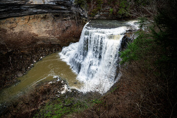 Waterfall cascading into a muddy river gorge in autumn © Natures TV 