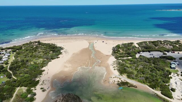 Aerial drone view of the mouth of the Anglesea River merging into the ocean at Anglesea Main Beach along the Great Ocean Road in Victoria, Australia.&nbsp;The shallow estuary channel running through&nbsp;sands.